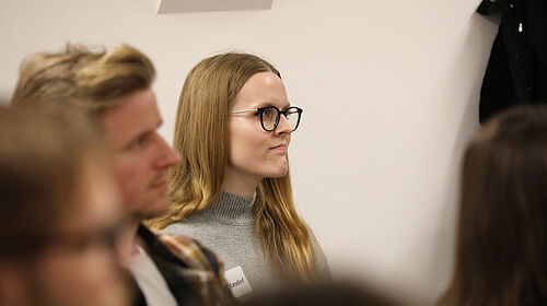 Ruth Kasdorf sitzend. Im Vordergrund sitzt ein Doktorand der Hochschule Wismar. Sie schauen beide einen Vortragenden des Kolloquiums an, der nicht im Bild zu sehen ist.