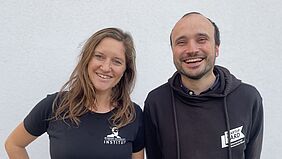 Carolin und Enrico stehen nebeneinander. Beide haben schwarze T-Shirts an. Auf Carolins steht "Robert Schmidt Institut" und auf Enricos "StartUpYard".