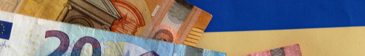 Es sind Geldscheine zu sehen, die auf einer Karte liegen, auf der vor blau-gelbem Hintergrund "Spendenaufruf" steht.