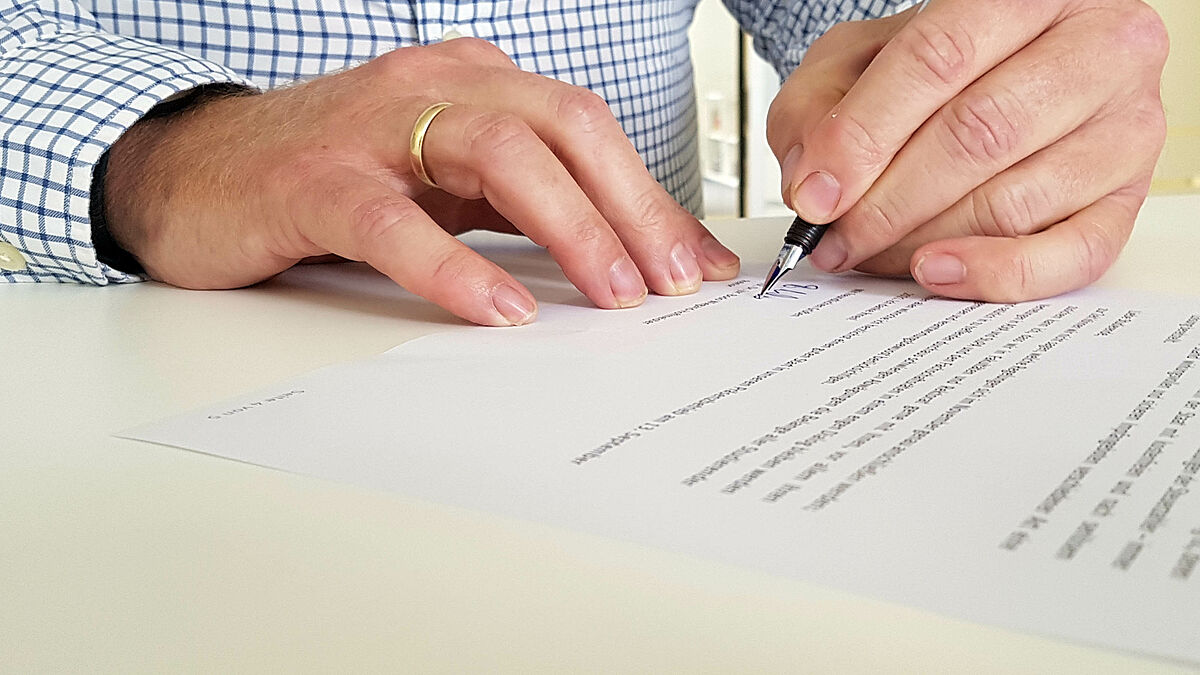 Rektor unterschreibt Im Bild sind die Hände des REktors während des Unterschreibens zu sehen