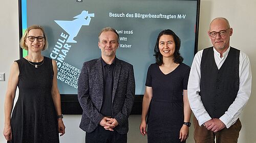 Vier Personen stehen schauen lächelnd in die Kamera.