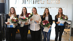 Im Bild sind die fünf ausgezeichneten Studentinnen mit Blumensträußen zu sehen.