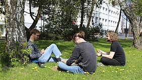 Drei Studierende genießen das Frühlingswetter auf dem Wismarer Campus