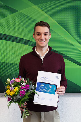 Mattis Plant mit Bachelorpreis geehrt Mattis Plant hält Urkunde und Blumenstrauß nach der Auszeichnung seiner Bachelorarbeit.