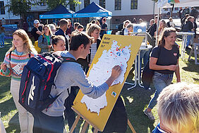 Ein Student befestigt einen Pin auf einer Landkarte, die auf einer Tafel befestigt ist.