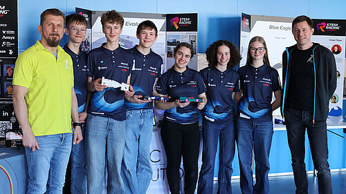 Die drei Schülerinnen und drei Schüler des Teams stehen nebeneinander, eingerahmt von den Professoren. Sie tragen einheitliche dunkelblaue T-Shirts mit dem Teamnamen.