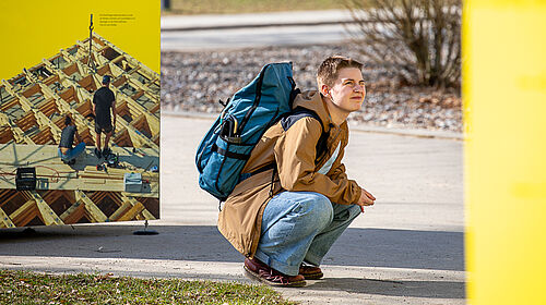 Die Frau kauert nah an einer Stele und liest konzentriert.