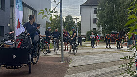 Am linkenbildrand ist ein Lastenfahrrad mit einer WErbeflagge zu sehen. Dahinter sind vier Personen im Gespräch. Rechts stehen die Pferde und weitere Personen.