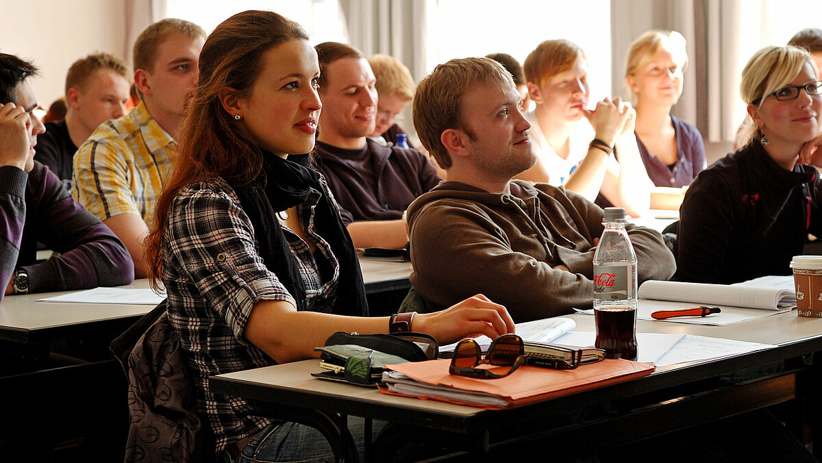 Das Bild zeigt interessiert zuhörende Studierende in einem Seminarraum.