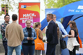 Es sind Personen vor dem sehr bunten Stand der IHK zu Schwerin zu sehen.