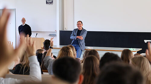 Prof. Dr Kai Neumann is standing in front of a large group of students in a lecture theatre.