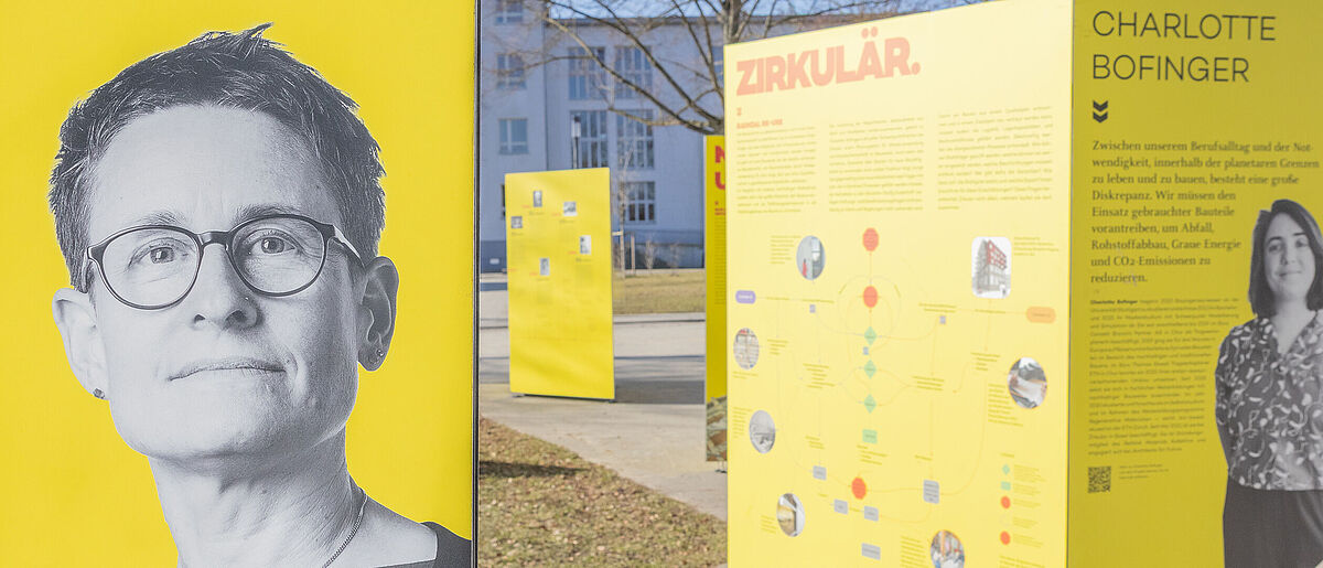 Outdoorausstellung mit großen gelben Flächen im Sonnenschein, darauf mehrere Fotos von Bauingenieurinnen und erklärende Texte