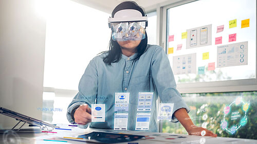 Introduction_Image Studiengang Wirtschaftsinformatik Master Eine Frau mit AR Brille sieht vor sich virtuelle Tabs vor einem Tisch