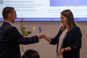 Die beiden Personen stehen sich gegenüber. Im Hintergrund ist noch die Präsentation der Preisträgerin zu sehen.