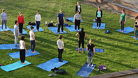 Im Bild sind Teilnehmerinnen eines Yogakurses auf der Campuswiese