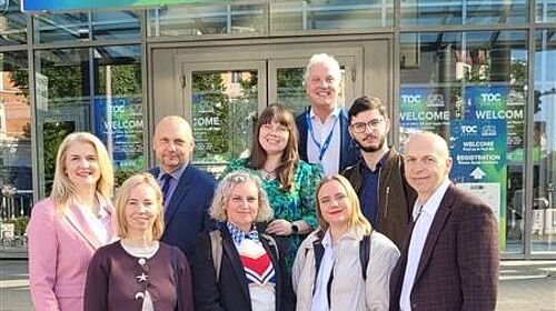 Mehrere Projektpartner des DigiTechPort2030-Konsortiums stehen vor dem Eingang der TOC Europe 2026 in Hamburg. Über ihnen befindet sich ein großes Willkommensschild der Fachmesse.