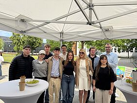 Students present their project results A group of students is standing with Prof. Dr Jantina Nord under a pavilion in front of the university lawn.