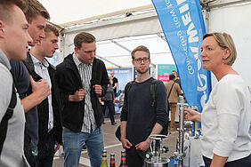 Fünf Studenten lassen sich an einem Stand beraten.