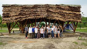 Es ist eine Gruppe vor dem von ihnen konzipierten und errichteten Gemeinschaftshaus im peruanischen Iquitos zu sehen.