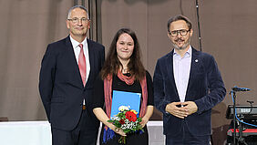 Gruppenbild der Gratulanten Torsten Habicht (rechts) und Prof. Dr.-Ing. Ingo Müller (links) sowie der Preisträgerin Meike Schlensog auf der Bühne während der Feierlichen Exmatrikulation.