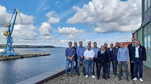 Die Gruppe steht auf der Dachterasse vor dem Konferenzraum des TZF. Über ihr ist ein wunderschöner Himmel mit Wolken zu sehen.