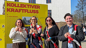 Die vier Frauen stehen nebeneinander. Sie haben das durchgeschnittene Band um ihren Hals gehängt.