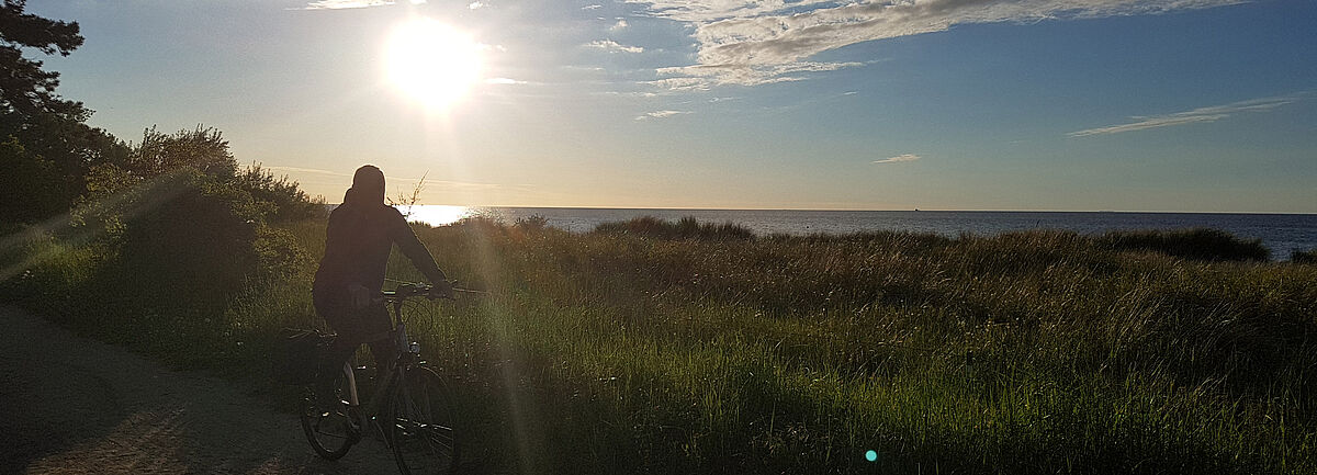 Radfahrer an Küste vor Sonnenuntergang
