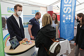 Ein ehemaliger Student berät eine Studentin am Stand der Firma, in der er jetzt arbeitet.