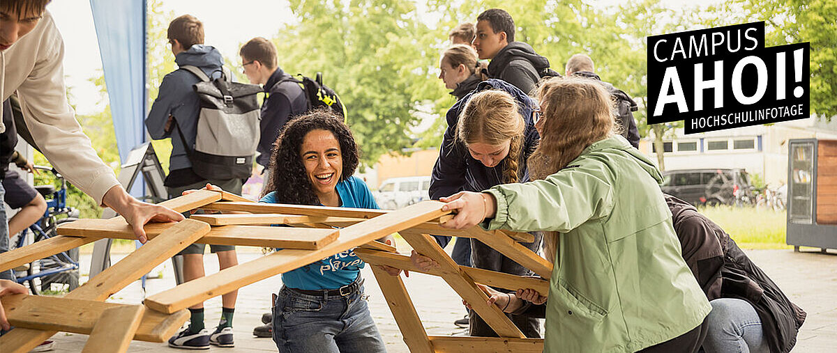 Campus Ahoi! Hochschulinfotage. Eine Gruppe von jungen Menschen baut gemeinsam eine Brücke aus Holzlatten - ohne Nägel oder Kleber
